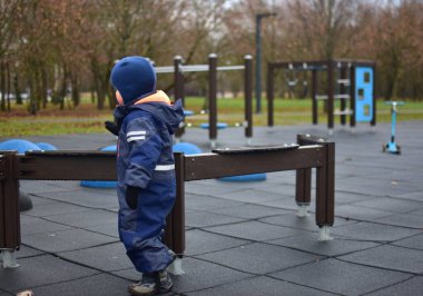 Küçük çocuk halk parkında eğleniyor. Kışın soğuk havada dışarıda oynayan bir çocuk..