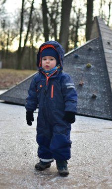 Küçük çocuk kışın oyun bahçesinde ilginç taklitçilerle duruyor.