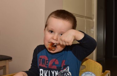 Küçük çocuk öğle yemeğini çatalla yiyor.