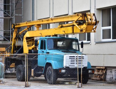 Eski usul Rus vinç kaldırıcı vinç servisi okul binasının yanında duruyor. Sovyet mirası paslı vinç kamyonu.