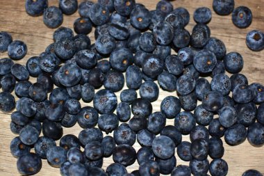 Ahşap masa manzarasına yayılmış taze yaban mersinleri. Tahta masaya bir sürü böğürtlen düştü..