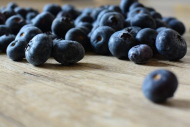 Ahşap masa manzarasına yayılmış taze yaban mersinleri. Tahta masaya bir sürü böğürtlen düştü. Makroyu kapat.