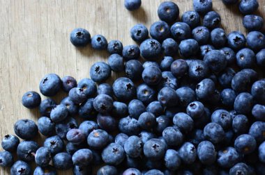 Ahşap masa manzarasına yayılmış taze yaban mersinleri. Tahta masaya bir sürü böğürtlen düştü..