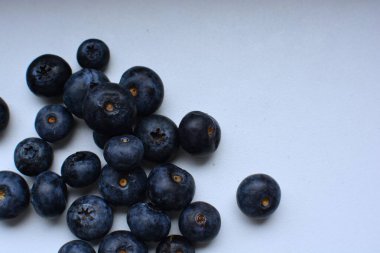 Taze yaban mersinleri beyaz masaya yayılmış. Üst manzara makrosu yakın. Beyaz yüzeyde bir sürü böğürtlen.