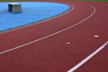 Sol tarafta mavi spor sahası olan kırmızı koşu pisti.