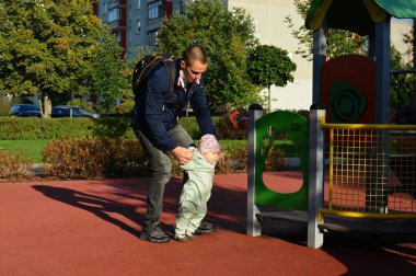 Babası küçük kızına oyun alanında yürümeyi öğretiyor. Babam Eylül 'de kızıyla vakit geçirir. Yavru kız ilk adımları.