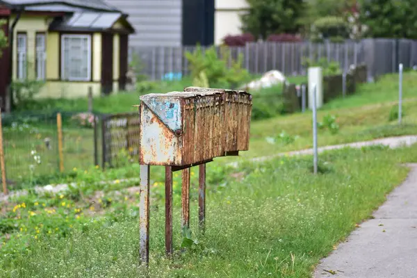 Kırsal kesimde eski, paslı metal posta kutuları. Yeşillik ve çimlerle çevrili, yıpranmış ve antika görünümlü. Terk edilmeyi, nostaljiyi ya da kırsal iletişim sistemlerini temsil eder.