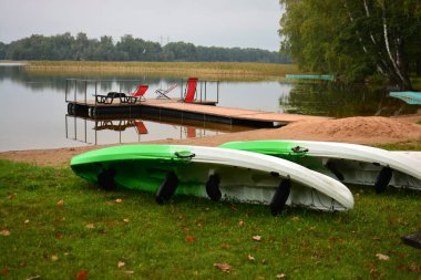 Göl kıyısında kanolar, iskele ve koltuklar..