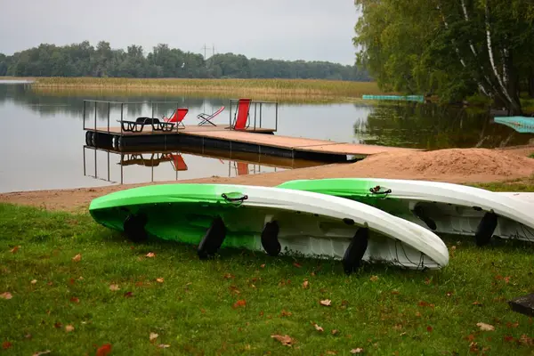 Göl kıyısında kanolar, iskele ve koltuklar..