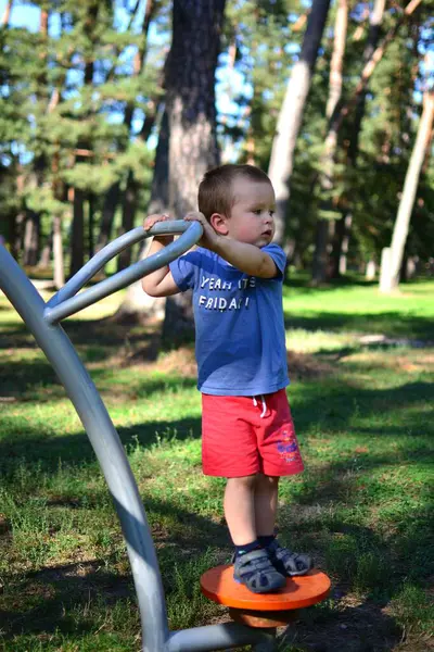 Güneşli bir yaz gününde parkta küçük çocuk spor aletleriyle antrenman yapıyor. Açık havada spor yapan bir çocuk..