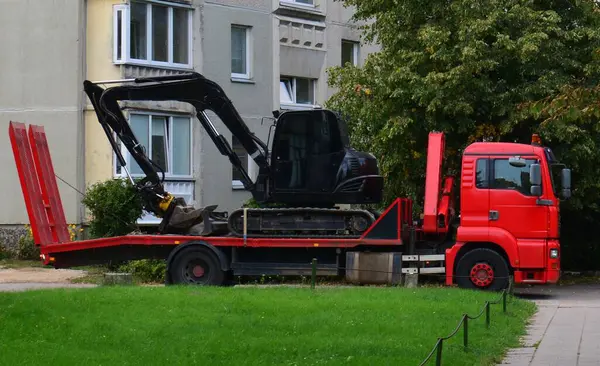 Mini kazıcı, apartman bloklarının yakınındaki kamyon römorkuna yüklendi..