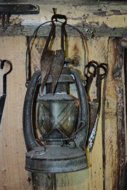 Duvardaki eski ahırda eski koyun tüyü makasının yanında asılı eski paslı gaz lambası. İçinde eski model bir gaz lambası asılı..