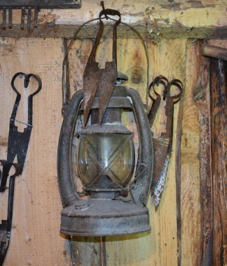 Duvardaki eski ahırda eski koyun tüyü makasının yanında asılı eski paslı gaz lambası. İçinde eski model bir gaz lambası asılı..