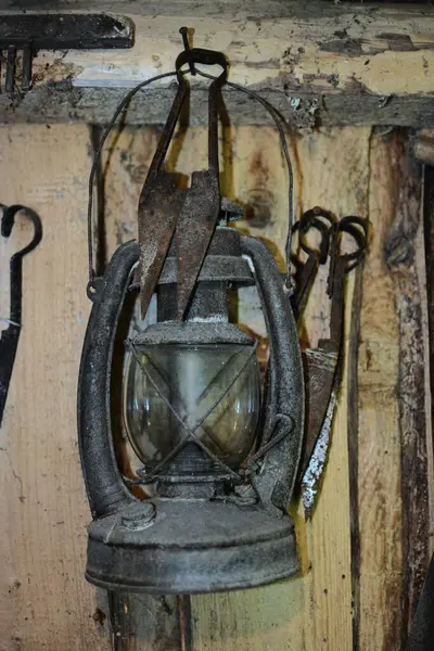 Duvardaki eski ahırda eski koyun tüyü makasının yanında asılı eski paslı gaz lambası. İçinde eski model bir gaz lambası asılı..