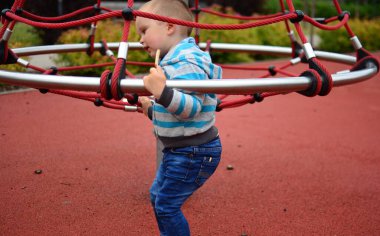 Çocuk yazın şehir parkında çocuk parkında oynuyor. Küçük çocuk yaz günü halk parkında eğleniyor..