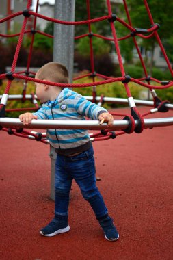 Çocuk yazın şehir parkında çocuk parkında oynuyor. Küçük çocuk yaz günü halk parkında eğleniyor..