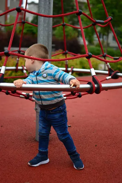 Çocuk yazın şehir parkında çocuk parkında oynuyor. Küçük çocuk yaz günü halk parkında eğleniyor..