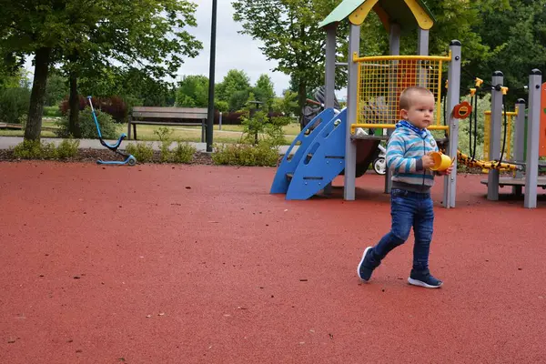Çocuk yazın şehir parkında çocuk parkında oynuyor. Küçük çocuk yaz günü halk parkında eğleniyor..