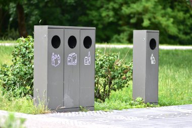 Halka açık bir parkta, solda plastik, kağıt ve cam için ayrı kaplar ve sağda ise genel atık kutuları ayırmak. Yer işaretleri körlerin çöp kutularını bulmasına yardımcı olur..