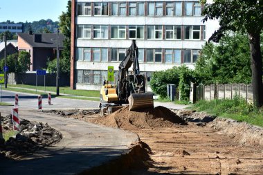 Yaz boyunca şehir karayolu inşaatında çalışan kazıcı. Toprak taşıma ekipmanları trafik işaretleri rehber araçları olarak yeni bir yola hazırlanıyor. Şehirdeki altyapı gelişimi.