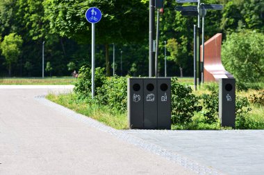 Parkın yakınındaki kaldırım boyunca çöp kutularını modern atık ayıklama. Çevre dostu geri dönüşüm istasyonu sürdürülebilirliği ve temiz kamu alanlarını teşvik eder. Etiketleri temizle uygun atık bertaraf kılavuzu.