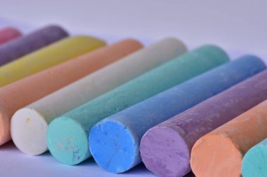 Düzgün sıra dizilmiş büyük tebeşir çubuklarının yan açısı. Sanatsal doku ve canlı renkler yaratıcı ifade, okul malzemeleri ve çocukların çizim araçlarını temsil eder.