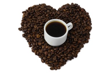 Espresso kahve fincanı kalp şeklinde kavrulmuş kahve çekirdekleri ile çevrili.