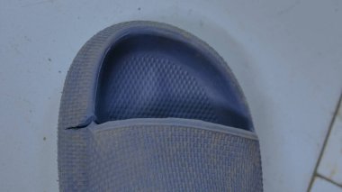 Kenarında yırtık mavi bir sandalet vardı.