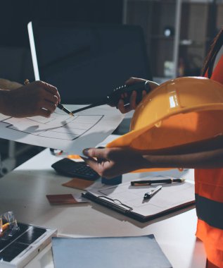 Endüstriyel mühendislerden oluşan bir ekip, fabrikadaki masada bulunan makine planlarını analiz ediyor. Fabrikada ya da üretim tesisinde çalışıyorum..