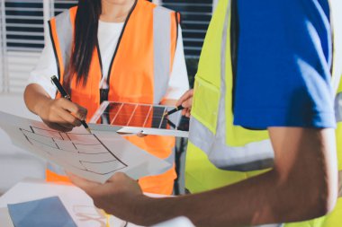 Endüstriyel mühendislerden oluşan bir ekip, fabrikadaki masada bulunan makine planlarını analiz ediyor. Fabrikada ya da üretim tesisinde çalışıyorum..
