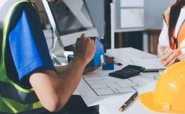 Endüstriyel mühendislerden oluşan bir ekip, fabrikadaki masada bulunan makine planlarını analiz ediyor. Fabrikada ya da üretim tesisinde çalışıyorum..