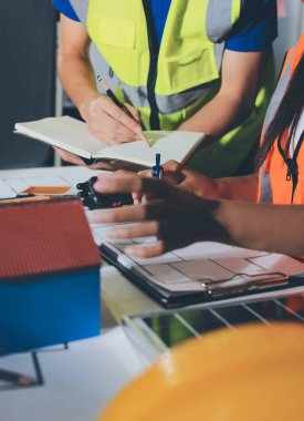 Endüstriyel mühendislerden oluşan bir ekip, fabrikadaki masada bulunan makine planlarını analiz ediyor. Fabrikada ya da üretim tesisinde çalışıyorum..