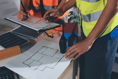 Endüstriyel mühendislerden oluşan bir ekip, fabrikadaki masada bulunan makine planlarını analiz ediyor. Fabrikada ya da üretim tesisinde çalışıyorum..