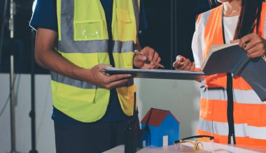 Endüstriyel mühendislerden oluşan bir ekip, fabrikadaki masada bulunan makine planlarını analiz ediyor. Fabrikada ya da üretim tesisinde çalışıyorum..