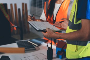 Endüstriyel mühendislerden oluşan bir ekip, fabrikadaki masada bulunan makine planlarını analiz ediyor. Fabrikada ya da üretim tesisinde çalışıyorum..