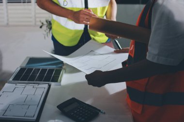 Endüstriyel mühendislerden oluşan bir ekip, fabrikadaki masada bulunan makine planlarını analiz ediyor. Fabrikada ya da üretim tesisinde çalışıyorum..