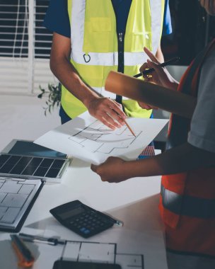 Endüstriyel mühendislerden oluşan bir ekip, fabrikadaki masada bulunan makine planlarını analiz ediyor. Fabrikada ya da üretim tesisinde çalışıyorum..