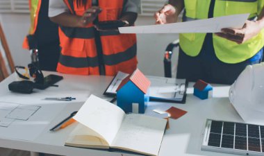 Endüstriyel mühendislerden oluşan bir ekip, fabrikadaki masada bulunan makine planlarını analiz ediyor. Fabrikada ya da üretim tesisinde çalışıyorum..