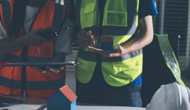 Endüstriyel mühendislerden oluşan bir ekip, fabrikadaki masada bulunan makine planlarını analiz ediyor. Fabrikada ya da üretim tesisinde çalışıyorum..