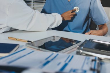 Bir doktor klinik randevusu sırasında hastanın kalbini incelemek için steteskop kullanır..