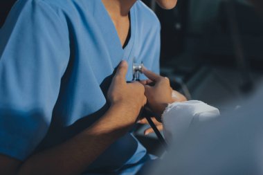 Bir doktor klinik randevusu sırasında hastanın kalbini incelemek için steteskop kullanır..