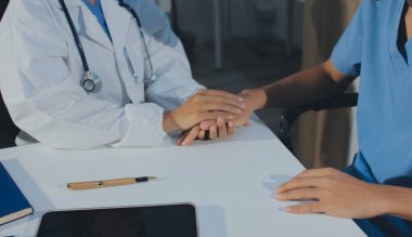 Doktor hastayı kontrol etmeye geldi ve cesaretlendirmek için elini sıktı. Hastanede tedavi edilenleri ve hastaları teselli etmek..