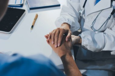 Doktor hastayı kontrol etmeye geldi ve cesaretlendirmek için elini sıktı. Hastanede tedavi edilenleri ve hastaları teselli etmek..