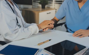 Doktor hastayı kontrol etmeye geldi ve cesaretlendirmek için elini sıktı. Hastanede tedavi edilenleri ve hastaları teselli etmek..