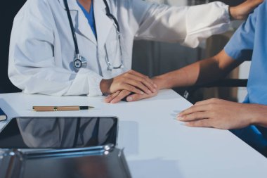 Doktor hastayı kontrol etmeye geldi ve cesaretlendirmek için elini sıktı. Hastanede tedavi edilenleri ve hastaları teselli etmek..