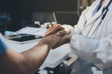 Doktor hastayı kontrol etmeye geldi ve cesaretlendirmek için elini sıktı. Hastanede tedavi edilenleri ve hastaları teselli etmek..