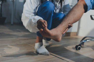 Fizyoterapist hastaya diz ağrısı için egzersiz yapmayı öğretiyor.