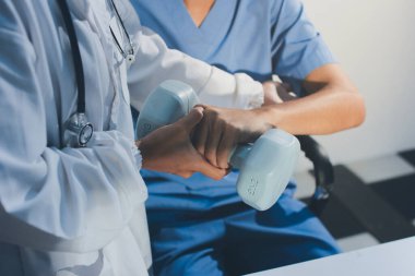 Hemşirenin desteğiyle el ağırlığı kullanan kişi