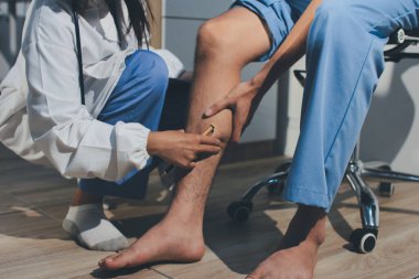 Fizyoterapist hastaya diz ağrısı için egzersiz yapmayı öğretiyor.