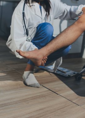 Fizyoterapist hastaya diz ağrısı için egzersiz yapmayı öğretiyor.